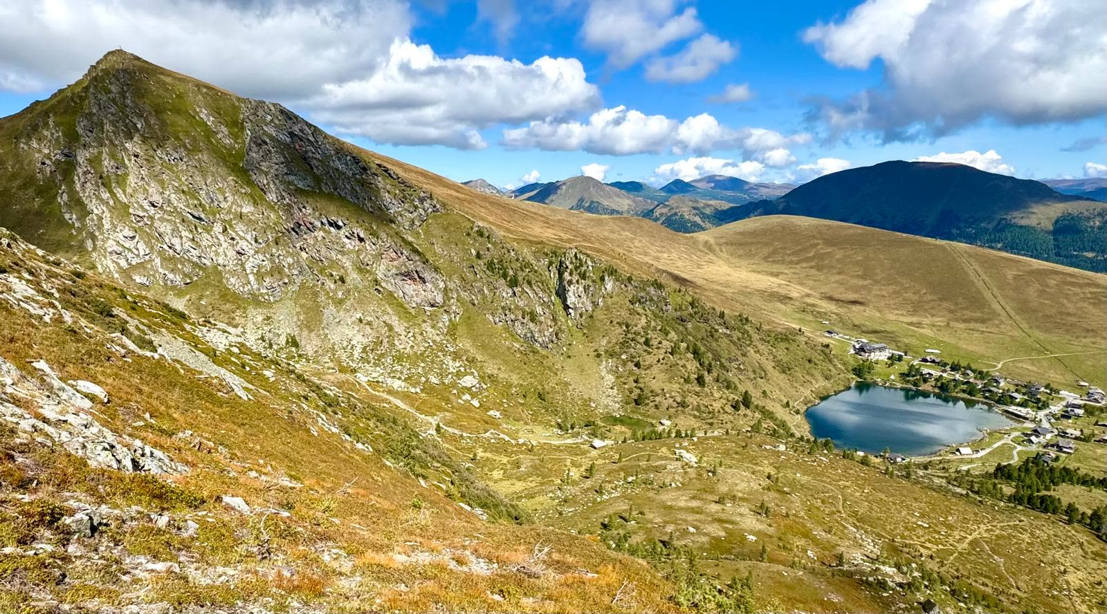 Der Falkertsee als tiefblauer Bergsee unterhalb der begrünten Nockberge